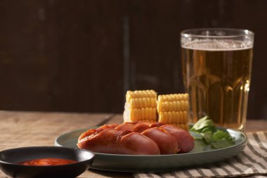 kupa bira ve ahşap masa tabakta Mısır ile ızgara sosis