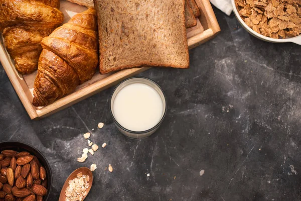 Breakfast with toasts, croissant and milk in glass on black tabletop