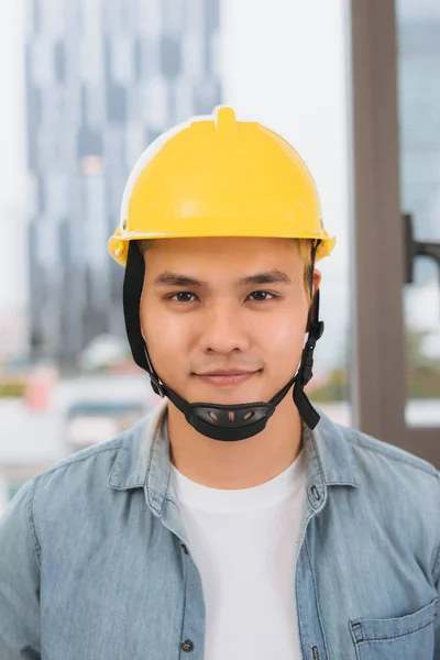 若い男建設現場で黄色いヘルメットと労働者 — ストック写真