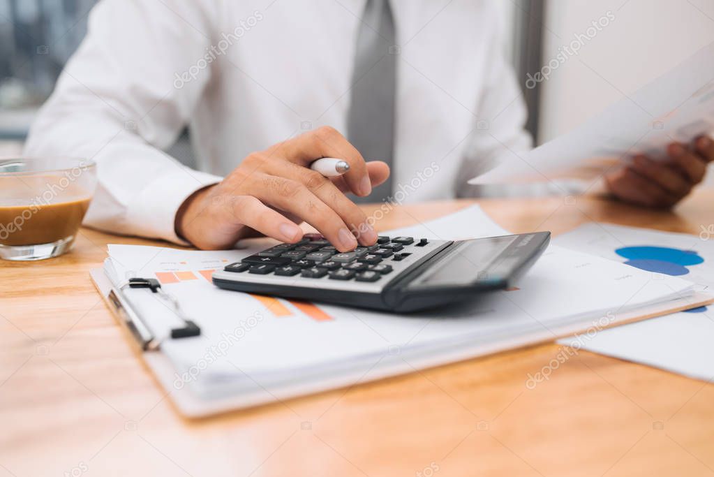 Partial view of businessman with calculator working at workplace with documents and laptop