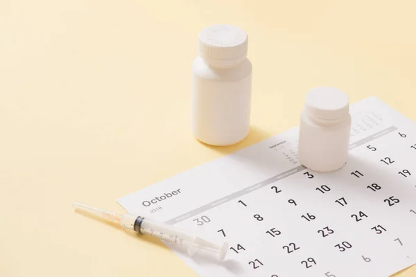 Bottles of medicines and syringe on a sheet of calendar