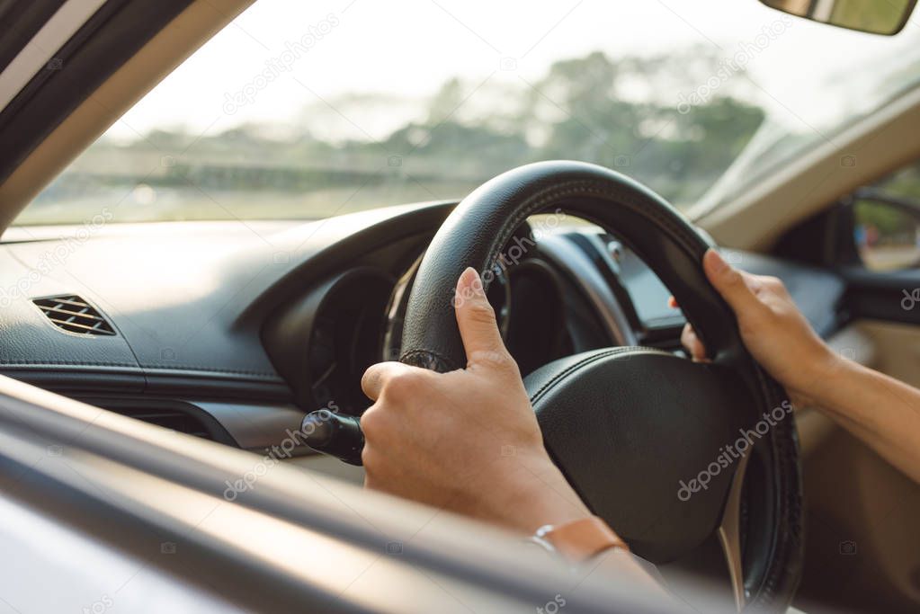 female hands on steering wheel on the right with country side view