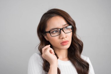 Elini yüzüne yakın tutarak, ciddi görünümlü, kopya alanı ile gri arka plan üzerinde duran çok emin düşünceli kız portresi kapatın