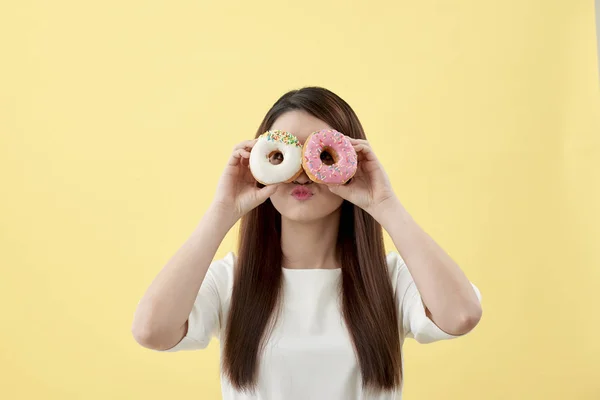 Привлекательная Азиатка Держащая Два Пончика Милым Улыбающимся Выражением Желтом Фоне — стоковое фото