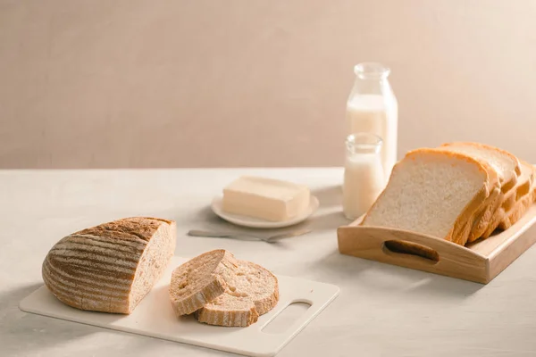 Частично Нарезанный Хлеб Тарелке Маслом Молоком Белом Столе — стоковое фото
