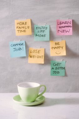 Group of New year Resolution Notes on pink, yellow, orange and green on wall written with message of diet, join gym, find love and be happy