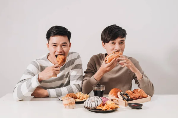 Two friends eating burgers. french fries, having fun and smiling