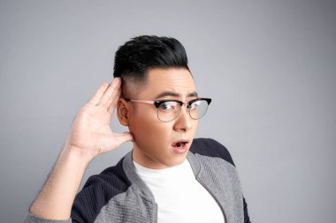 Beyaz arka plan üzerinde konuşma kulak misafiri olur genç casual adam portresi