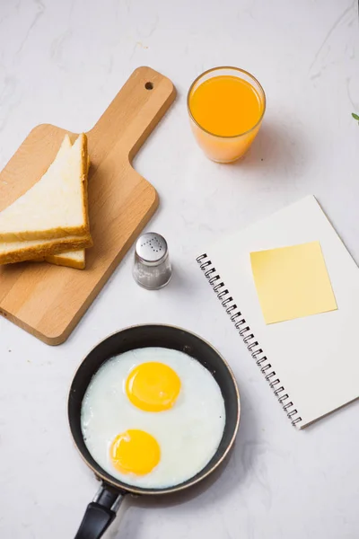 Jedzenie Procesie Smażone Jajka Patelni Tosty Sok Pomarańczowy Śniadanie Białym — Zdjęcie stockowe