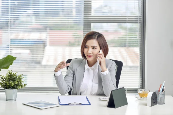 Veselá Asijské Žena Mluví Mobilním Telefonu Zatímco Sedí Stole Notebookem — Stock fotografie