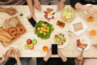 Arkadaşlarınızla akşam yemeği zevk. Grup birlikte ahşap masada otururken yemeğe insan Üstten Görünüm