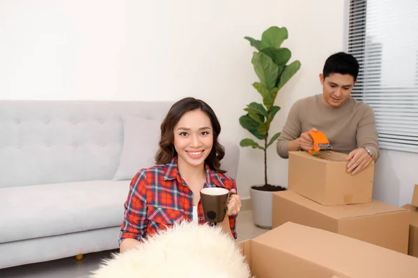 Excited young couple unpacking carton boxes with cozy home stuff