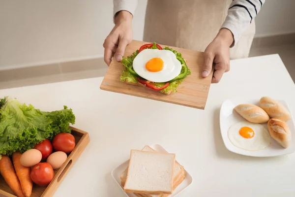 Τα χέρια του ανθρώπου προετοιμασία πρωινού με σάντουιτς με αυγό ποσέ — Φωτογραφία Αρχείου