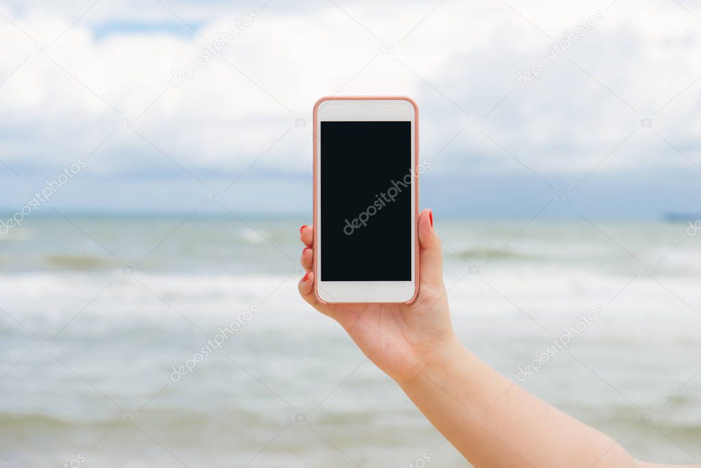 Hand holding phone at sea , mobile template for text in side