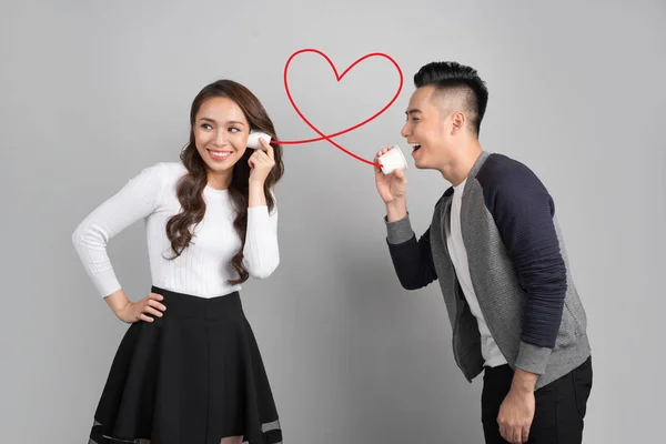 Young asian couple with can phone isolated on gray background