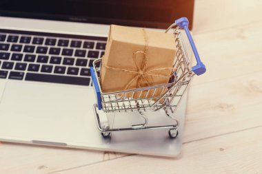 Alışveriş zamanı. Bir dizüstü bilgisayar ve alışveriş sepeti hediye kutusu ile sarılmış 