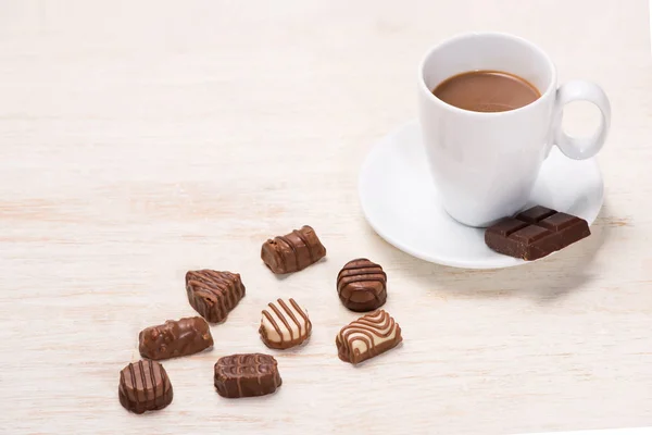 Стакан шоколадного молока и шоколадных конфет на столе — стоковое фото