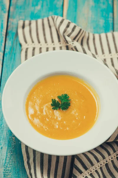 Pumpkin and carrot soup with cream and parsley on blue  wooden b — Stock Photo, Image