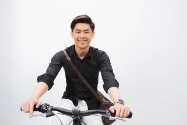 Genç yakışıklı Asya adam beyaz duvar zemin karşı bir bisiklet üzerinde oturur