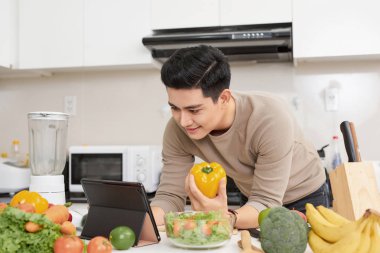 Tablet bilgisayar kullanan adam evde mutfak, yemek.