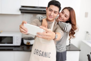 Mutlu çift yemek yemek ve onların çatı katı mutfak evde alarak selfie. Sebze salatası hazırlama ve sosyal ağ için kopya alanı fotoğrafçılık