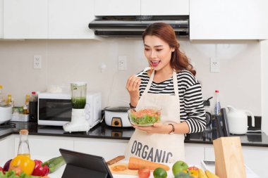 Evde sağlıklı yiyecekler. Mutlu kadın mutfakta sebze ve meyve hazırlıyor..