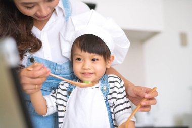Anne ve kızı mutfakta birlikte yemek pişiriyorlar.