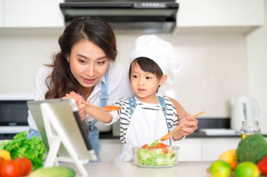 Anne ve kızı mutfakta birlikte yemek pişiriyorlar.