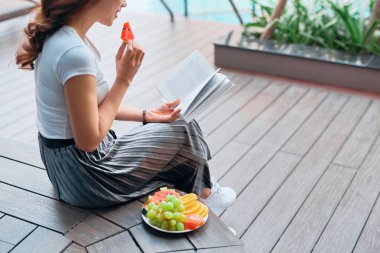 Oldukça neşeli kadın portresi rahatla ve okuma kitap tatil yaz sezonu resort yüzme havuzunda