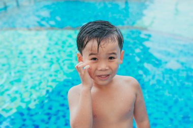 Stres Asyalı çocuk havuzu arka plan üzerinde yüz tırmalamak. Yaz konsepti
