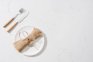 Beslenme kavramı. Kaşık, çatal ve beyaz tabak beyaz taş zemin üzerinde.