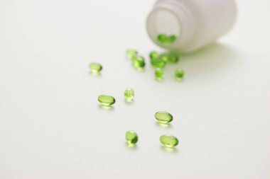 Yeşil beyaz arka plan üzerinde izole bir şişe içinde kapsüller