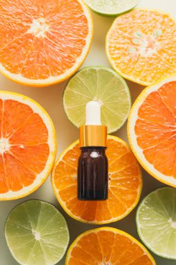 Limon, portakal, mandalina ve beyaz arka planda C vitamini ile kahverengi şişe..