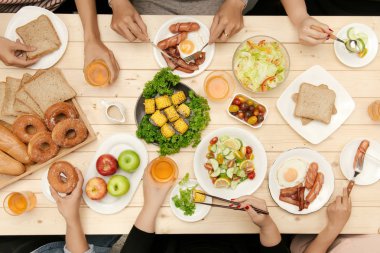 Arkadaşlarınızla akşam yemeği zevk. Grup birlikte ahşap masada otururken yemeğe insan Üstten Görünüm
