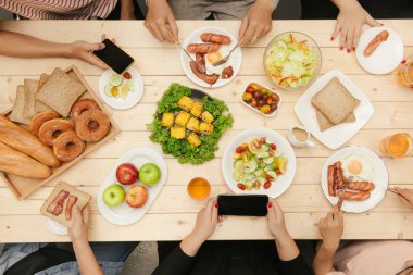 Arkadaşlarınızla akşam yemeği zevk. Grup birlikte ahşap masada otururken yemeğe insan Üstten Görünüm