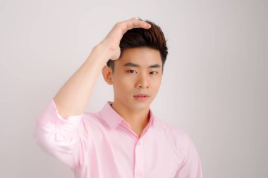 Asya yakışıklı stand ve gri arka plan üzerinde poz gülümse