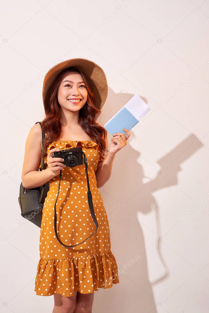 Expressive tourist woman in summer casual clothes, hat holding passport, tickets isolated on beige background. Female traveling abroad to travel weekends getaway. Air flight journey concept
