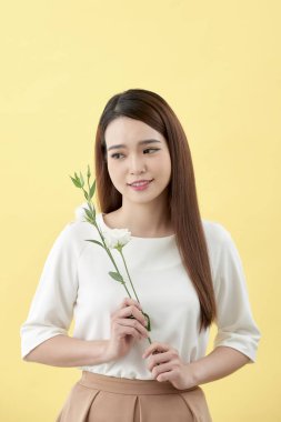 Bayan 20'li yaşlarda holding beyaz lisianthus çiçek sarı arka plan üzerinde güzellik portresi