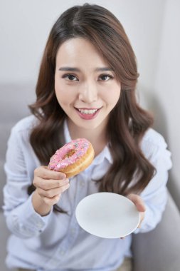 Evde çörek yiyen güzel genç kadının portresi.