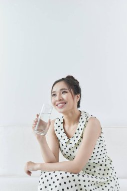 Evdeki kanepede oturan su içen kız. 