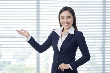 Gülümseyen genç kadın bir şey gösteriyor.