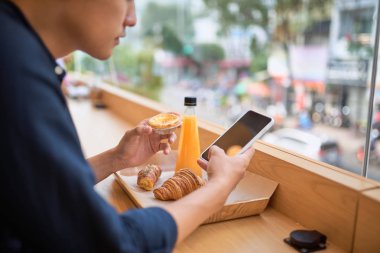 Erkek suyu ve tatlı tatlı ile Teras kafede oturur iken akıllı telefonu üzerinden internet sitesinde gerekli bilgi arar