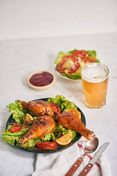 烤鸡腿烤上烤在黑盘子上的番茄酱在碗和莴苣叶 玻璃杯啤酒 — 图库照片