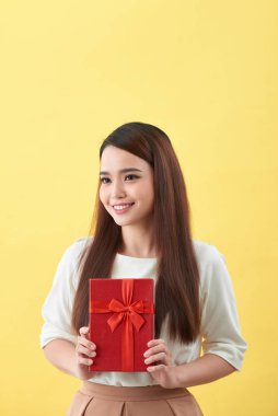 Asyalı kadın sarı arka planda bir hediye kutusu tutuyor