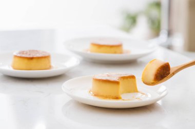 Kaşık ve plaka içinde tatlı kremsi karamel muhallebi bir ısırık parçası