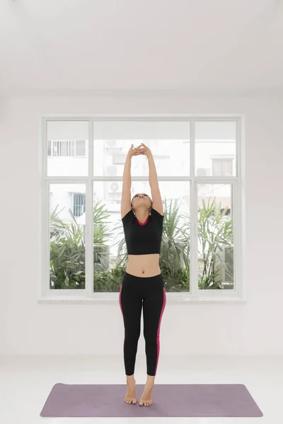 年轻的运动女子在窗口附近练习瑜伽 — 图库照片