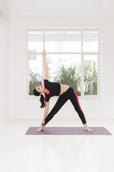 年轻迷人的女子练习瑜伽 站在勇士两次锻炼 穿着运动服 室内全长近窗 — 图库照片
