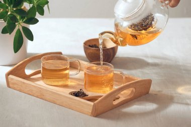 Ahşap servis tepsisinde cam Çaydanlık bir el çay dökme