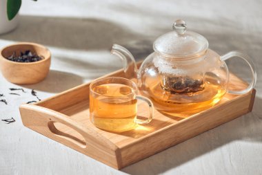 Ahşap bir arka planda şeffaf bir fincan ve çaydanlık çay