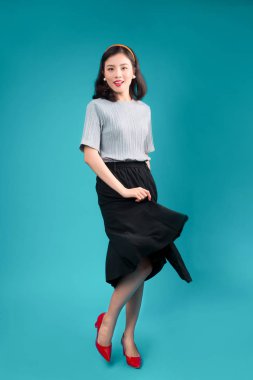 Gülümseyen Asyalı kadın tam vücut pin-up tarzı elbise üzerinde mavi giyinmiş..